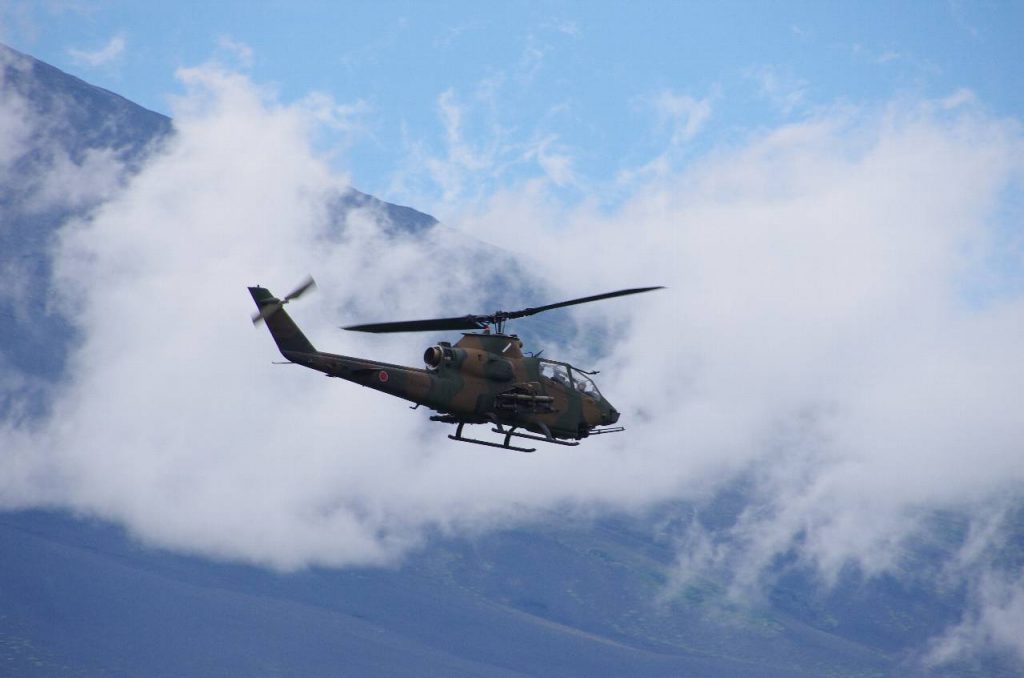富士山の稜線を背景に飛ぶ AH-1S ヘリコプター