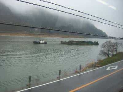 円山川を行く土砂運搬船と、それを曳くタグボート